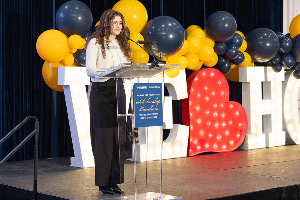 Stage setup with a clear podium and &ldquo;I &hearts; HCC&rdquo; sign at the Scholarship Luncheon.