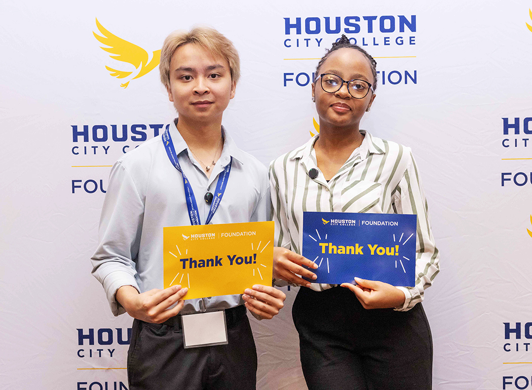 Two scholarship recipients holding &ldquo;Thank You&rdquo; cards in front of a Houston City College Foundation backdrop at the Scholarship Luncheon.